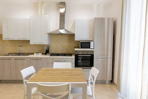 Una cucina moderna con mobili bianchi, un tavolo da pranzo in legno e un forno a microonde.