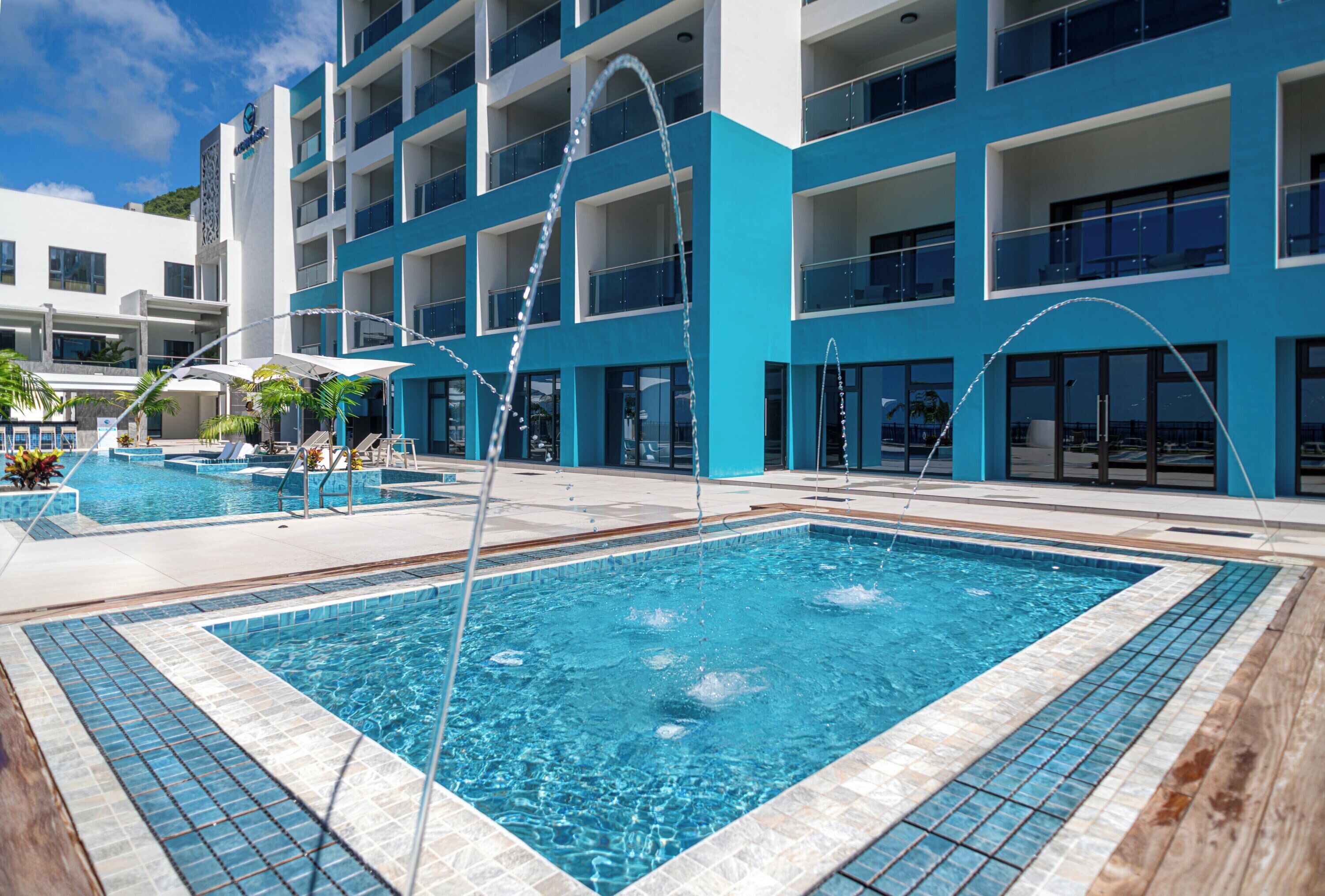 A hotel with a large outdoor swimming pool, multiple balconies, and a modern architectural design.
