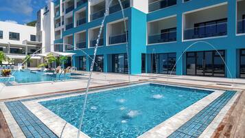 A hotel with a large outdoor swimming pool, multiple balconies, and a modern architectural design.