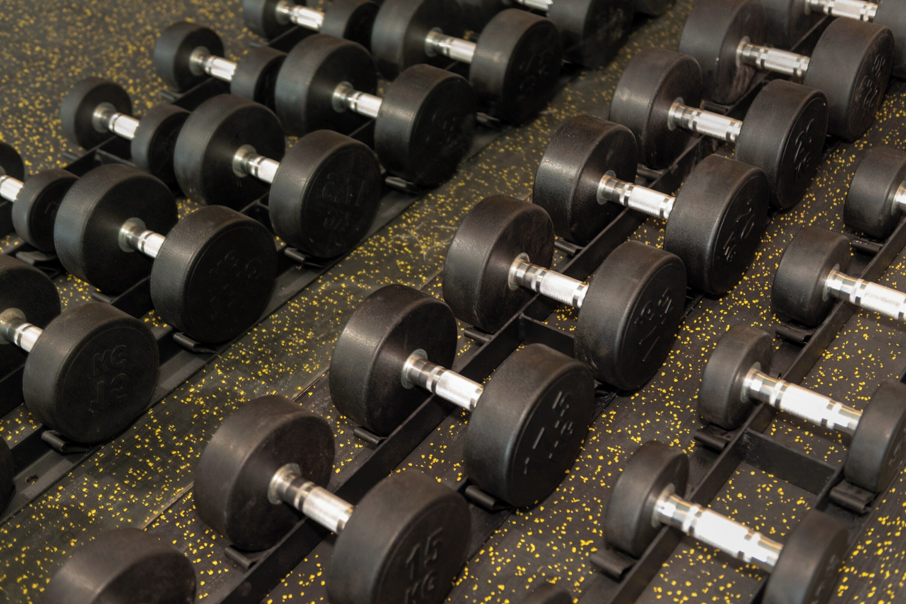 A rack of black dumbbells with weights labeled in kilograms.