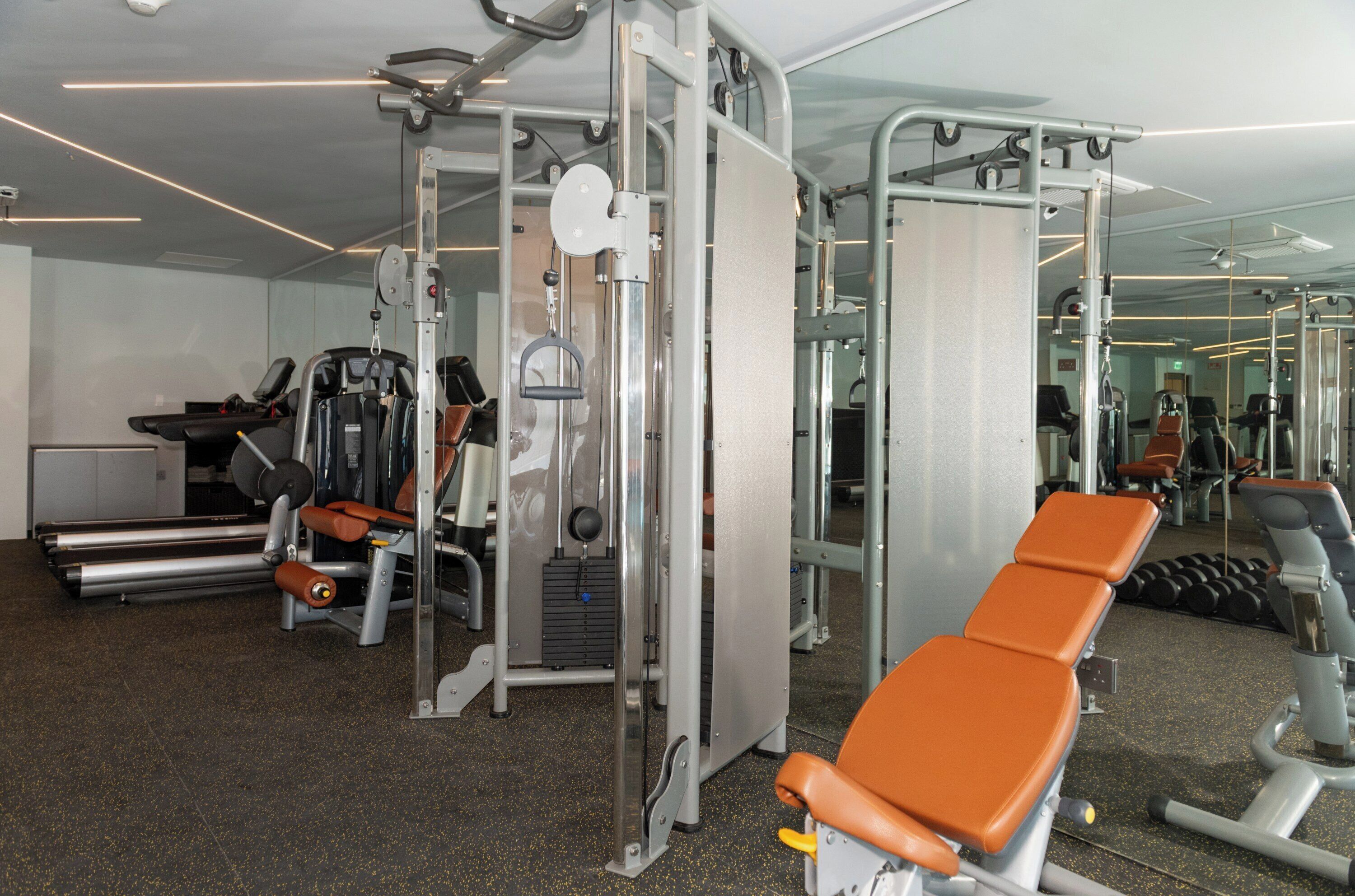 A gym with exercise equipment, mirrors, and a treadmill.