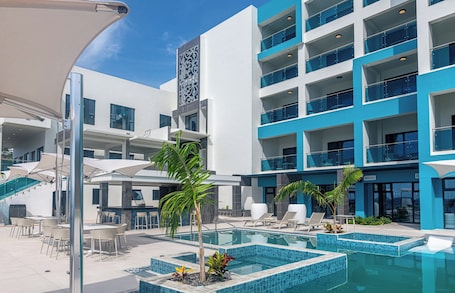 Una piscina al aire libre, sombrillas, sillones reclinables de piscina