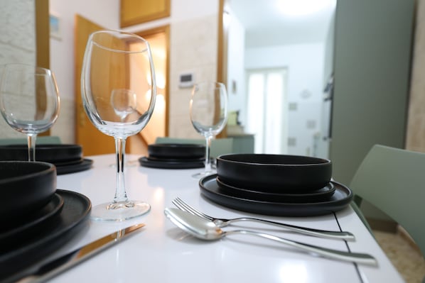 A dining table set with black plates, clear wine glasses, a fork, and a knife.