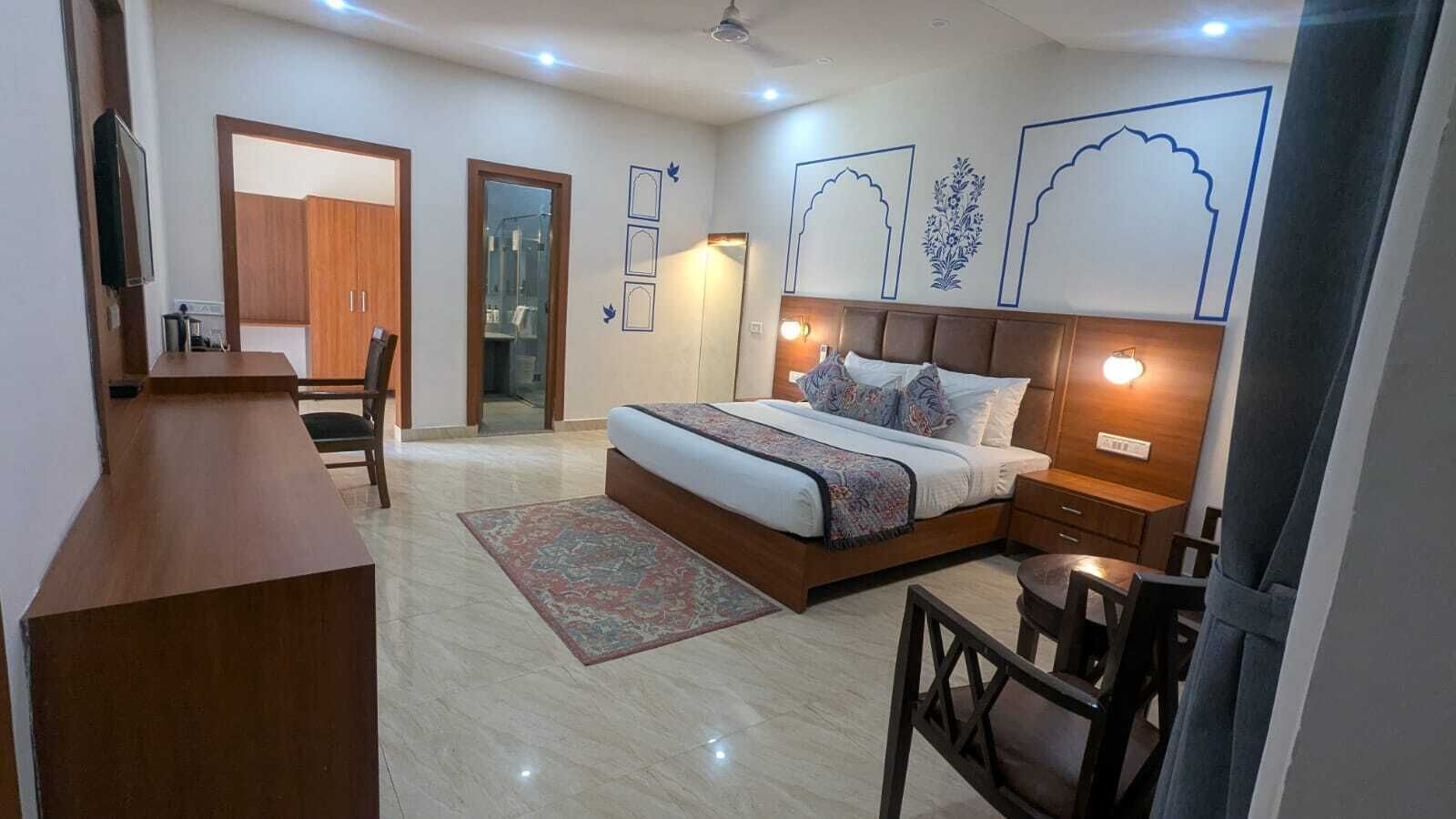A bedroom with a bed, bedside tables, a desk, and a chair.