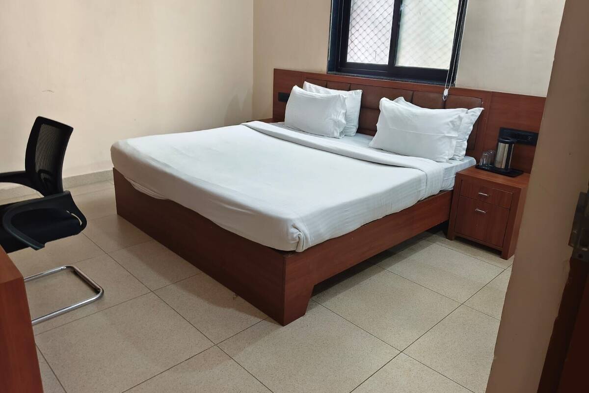 Ein Hotelzimmer mit Bett, Stuhl, Nachttisch und Fenster.