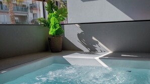 A hot tub with clear water, a potted plant, and a view of buildings outside. - G B Urban Spa by Cretanhouses (Heraklion)