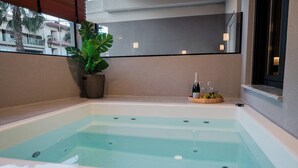 A modern indoor hot tub with clear water, a potted plant, and a bottle of wine on the edge. - G B Urban Spa by Cretanhouses (Heraklion)