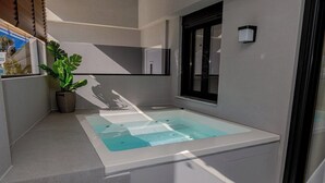 A modern bathroom with a glass-enclosed jacuzzi, a potted plant, and a window with blinds. - G B Urban Spa by Cretanhouses (Heraklion)