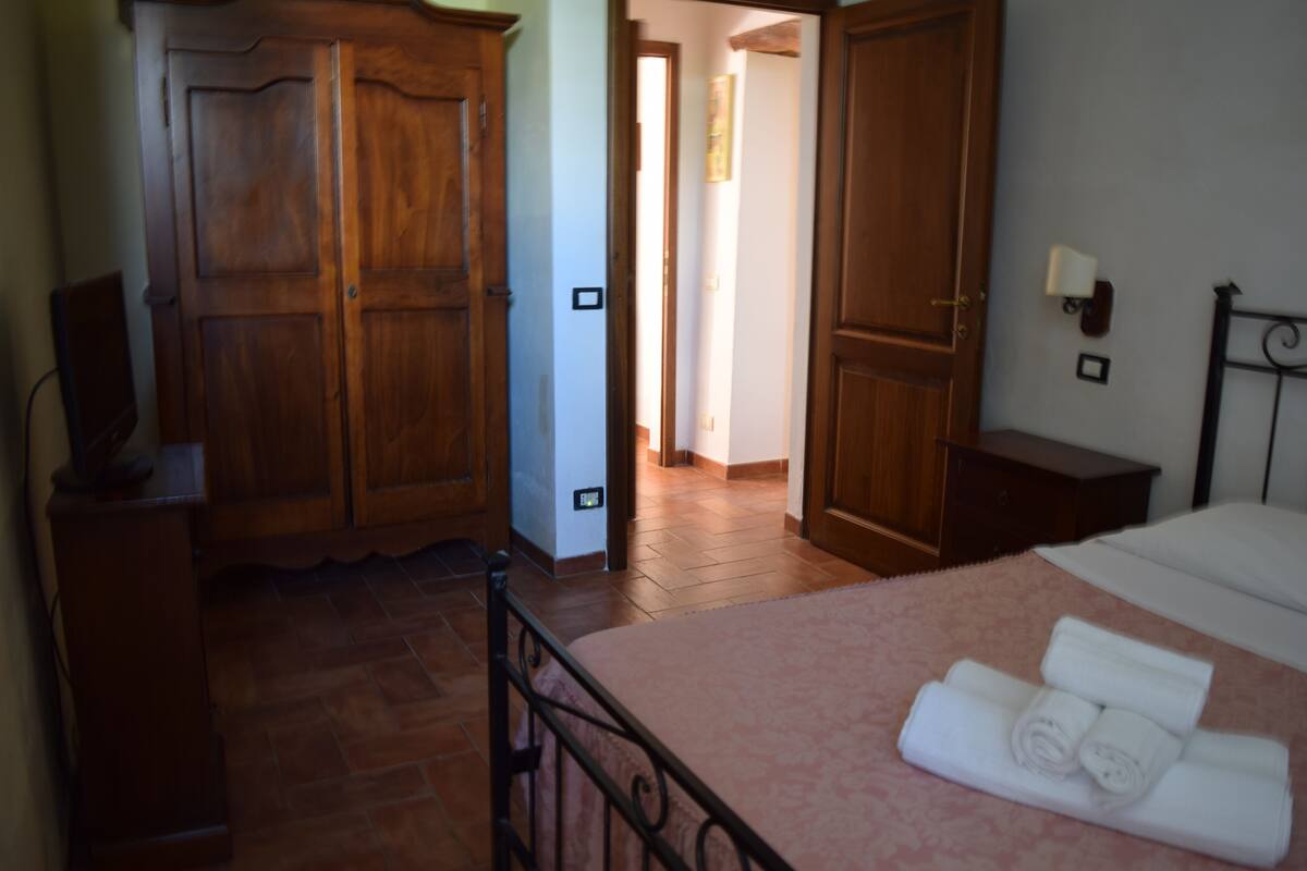 A bedroom with a bed, wooden wardrobe, and a nightstand.