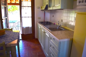 Apartamento básico, patio | Cocina privada | Frigorífico, horno, placa de cocina y utensilios de cocina