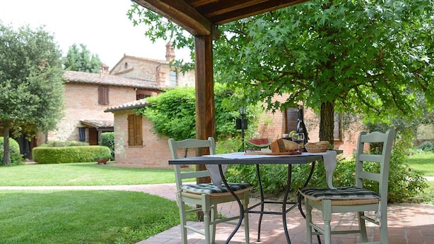 A covered patio with a table and chairs, a bottle of wine, and a basket of bread. - Oasi della Pergola  (Castiglione del Lago)