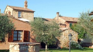 A stone building with a tiled roof, a small stone structure in front, and a lamp post. - Oasi della Pergola  (Castiglione del Lago)