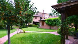 A well-maintained garden with a brick house, a paved pathway, and a small lawn area. - Oasi della Pergola  (Castiglione del Lago)