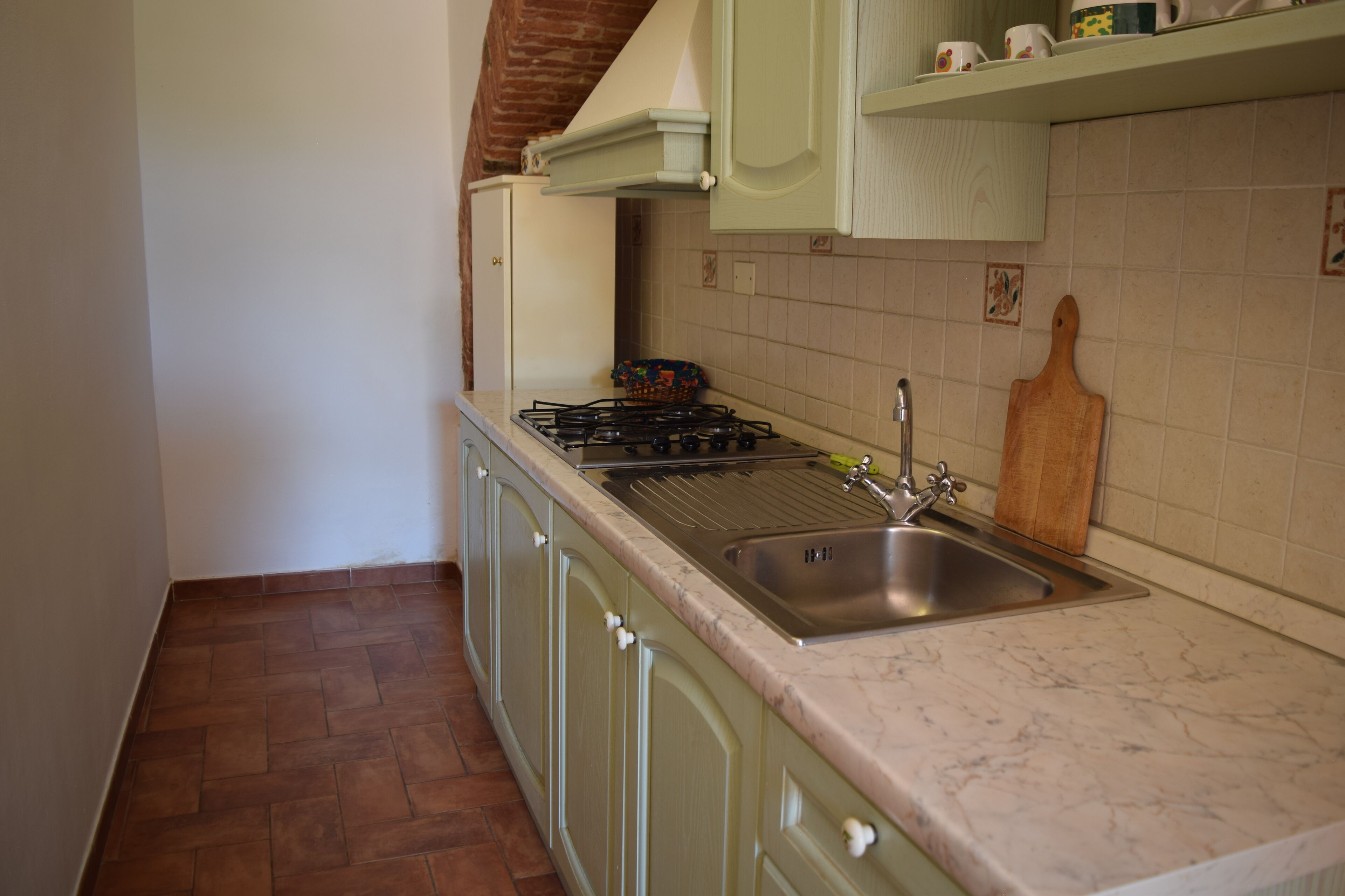 Une cuisine équipée d’une cuisinière à gaz, d’un évier et d’une planche à découper en bois.