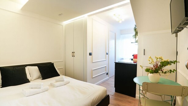 A bedroom with a bed, bedside tables, a desk, and a chair. - [Torino] San Salvario Attic Room (Torino)