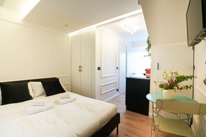 A bedroom with a bed, bedside tables, a desk, and a chair. - [Torino] San Salvario Attic Room (Torino)