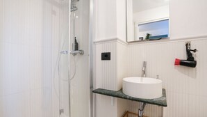 A bathroom with a glass shower enclosure, a white sink with a marble countertop, and a mirror with a view of the sky. - [Torino] San Salvario Attic Room (Torino)