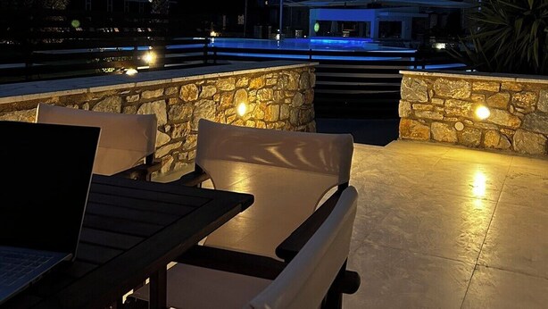 Un espace extérieur aménagé en terrasse, avec des murs en pierre, une piscine et une vue sur une montagne.