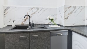 Una cocina moderna con lavavajillas integrado, salpicadero de mármol y grifo negro.