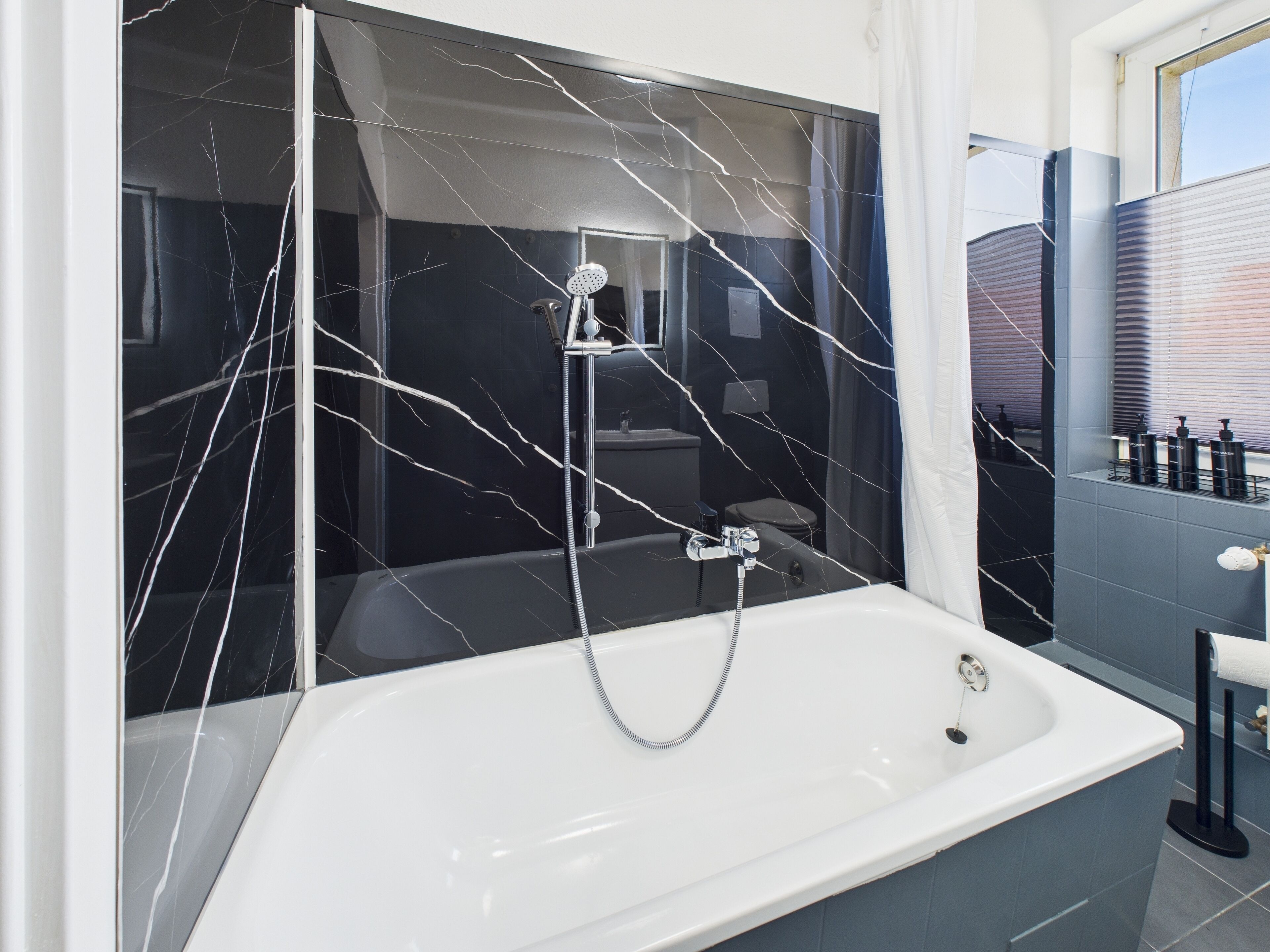 A modern bathroom with a large bathtub, a glass shower enclosure, and a vanity with toiletries.