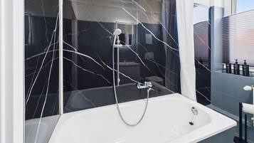A modern bathroom with a large bathtub, a glass shower enclosure, and a vanity with toiletries.