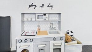 Una cocina de juguete para niños con microondas, horno y pileta.