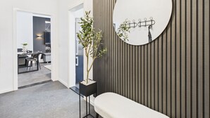 Un interior moderno con un banco, una planta en maceta y un espejo redondo en la pared.