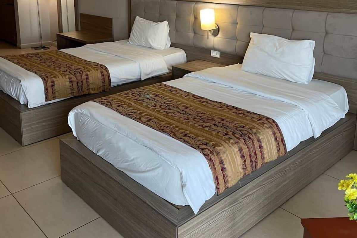 Habitación de hotel con dos camas, una mesita de noche, un espejo y una lámpara.