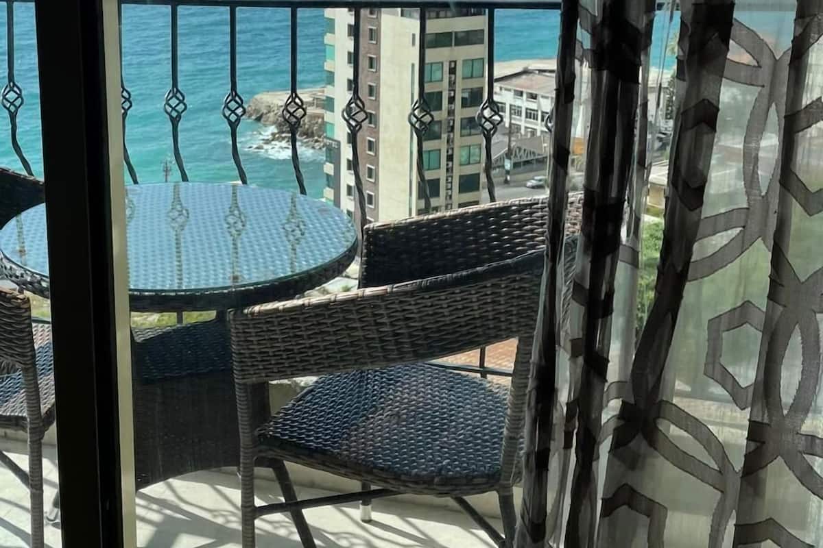 Un balcón con vistas al océano y al horizonte de la ciudad.