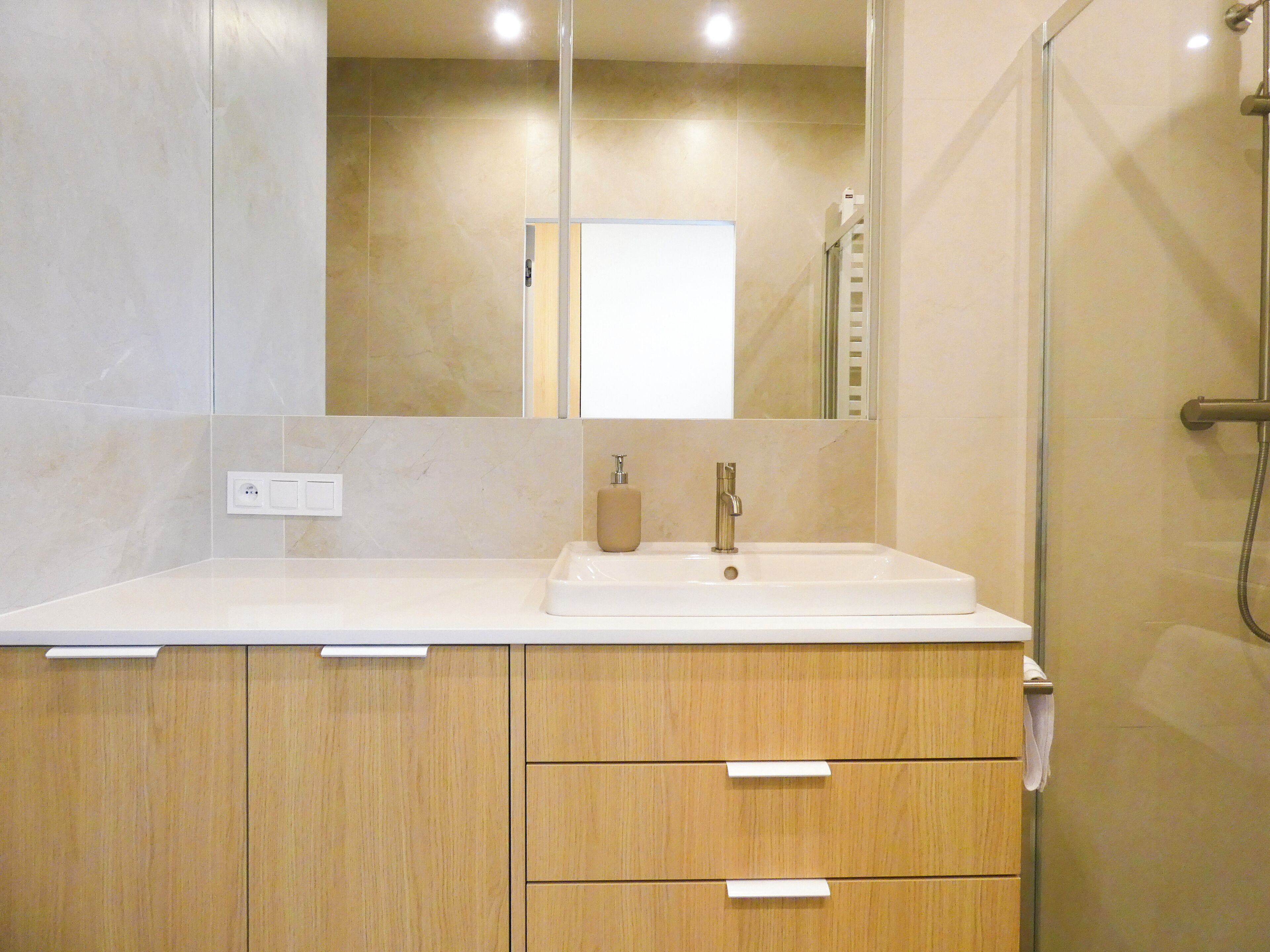 A bathroom with a white sink, a mirror, and wooden cabinets.
