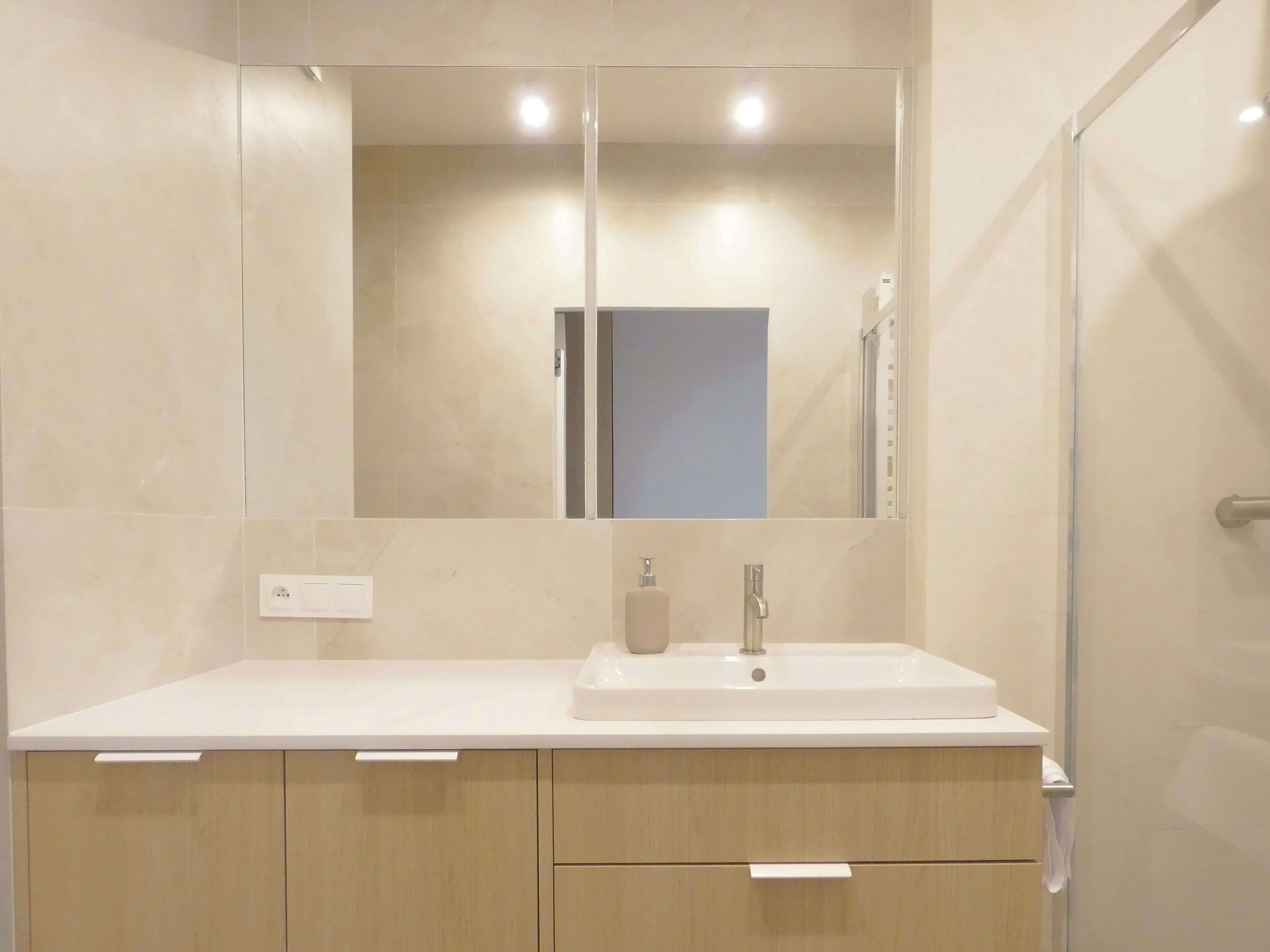 Une salle de bain moderne avec un lavabo blanc, un miroir et des meubles en bois.