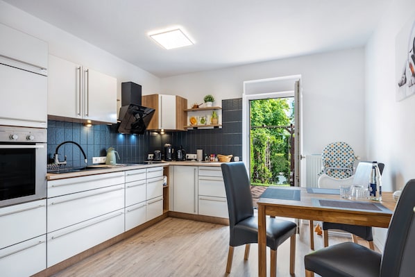 A modern kitchen with white cabinets, a wooden countertop, and a dining area with a table and chairs.