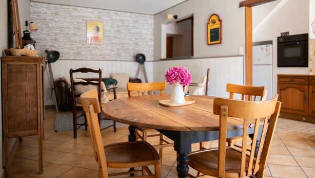 Ein Essbereich mit Holztisch und -stühlen, einer Blumenvase und einer Ziegelwand.