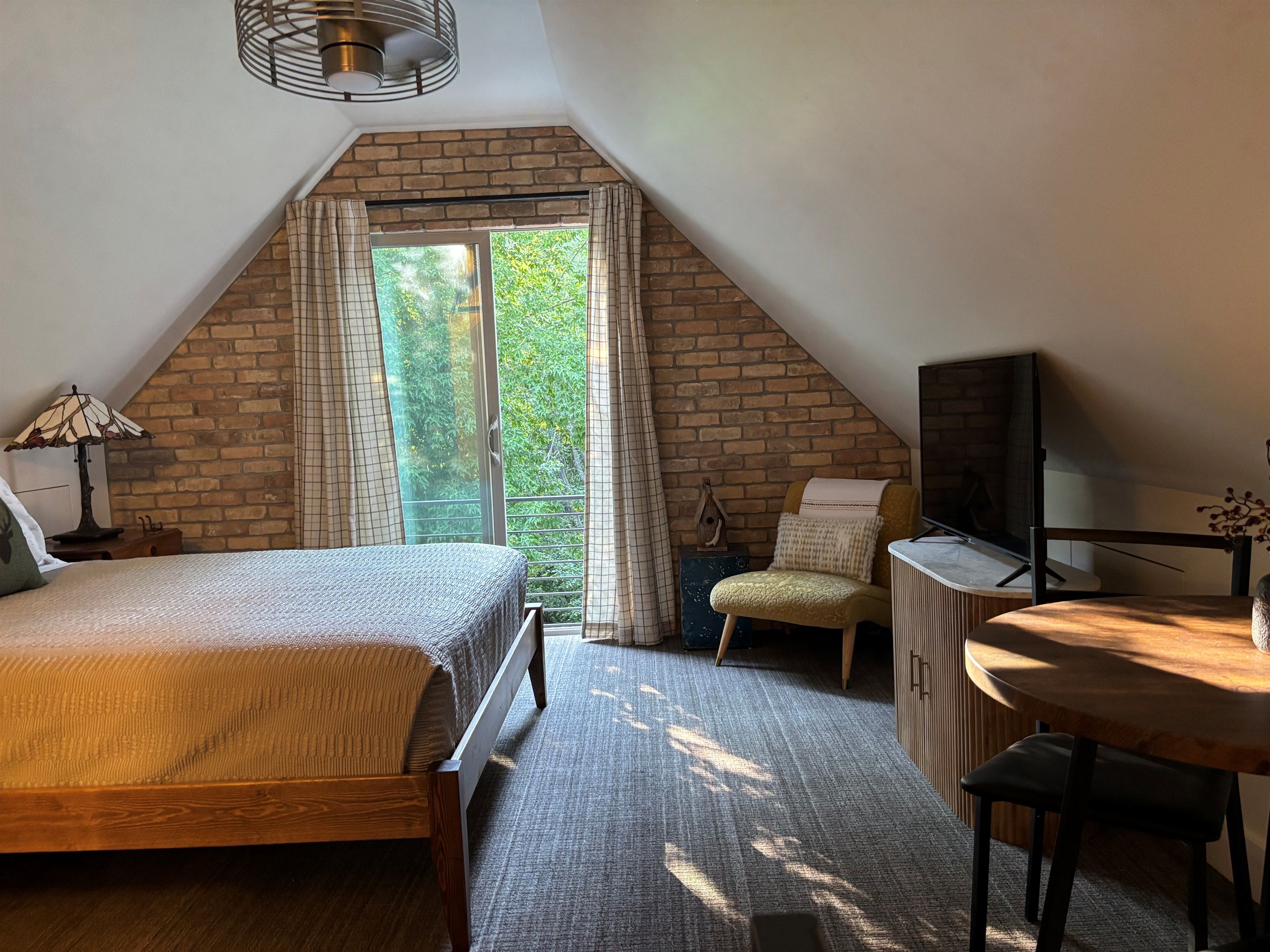 Bedroom with a brick wall, armchair, and TV