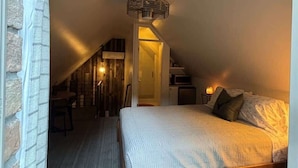 A bedroom with a sloped ceiling, a bed, a small desk, and a chair. - Chic Mountain Loft • Breathtaking Views (Provo Canyon)