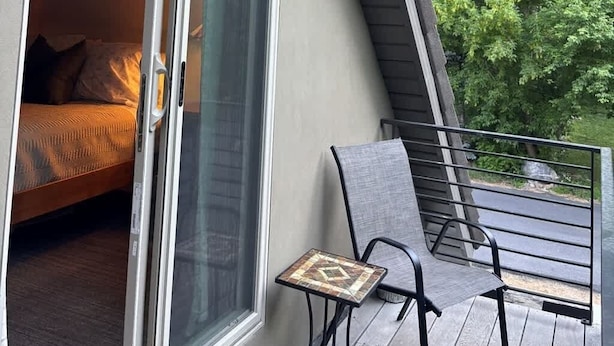 A room with a bed, a sliding glass door, a small table, and a chair. - Chic Mountain Loft • Breathtaking Views (Provo Canyon)