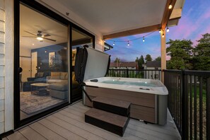A hot tub on a wooden deck with steps leading to a sliding glass door, overlooking a backyard with a patio and a house. - New Listing! Stylish Après-Ski Stay | Walk to Shuttle + Hot Tub (Fraser)