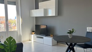 Ein modernes Wohnzimmer mit Flachbildfernseher, einem Esstisch und einer Topfpflanze.