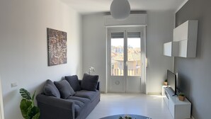 Ein modernes Wohnzimmer mit grauem Sofa, einem runden Couchtisch und einer Zimmerpflanze.
