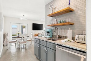 Una cocina moderna con armarios grises, encimera de mármol y horno empotrado.