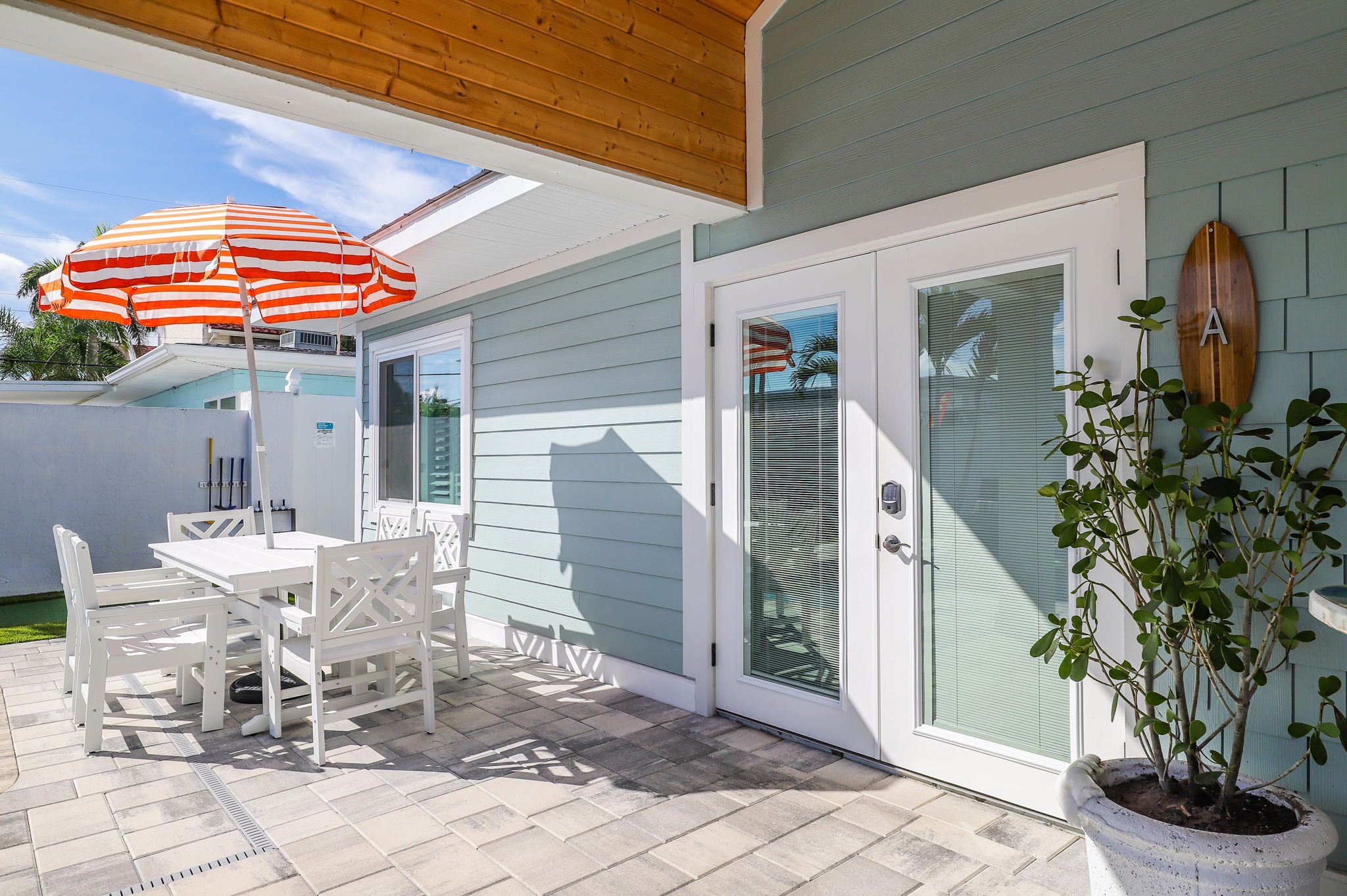 A patio with a table and chairs, a potted plant, and a sliding glass door.