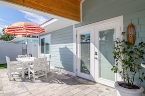 A patio with a table and chairs, a potted plant, and a sliding glass door.