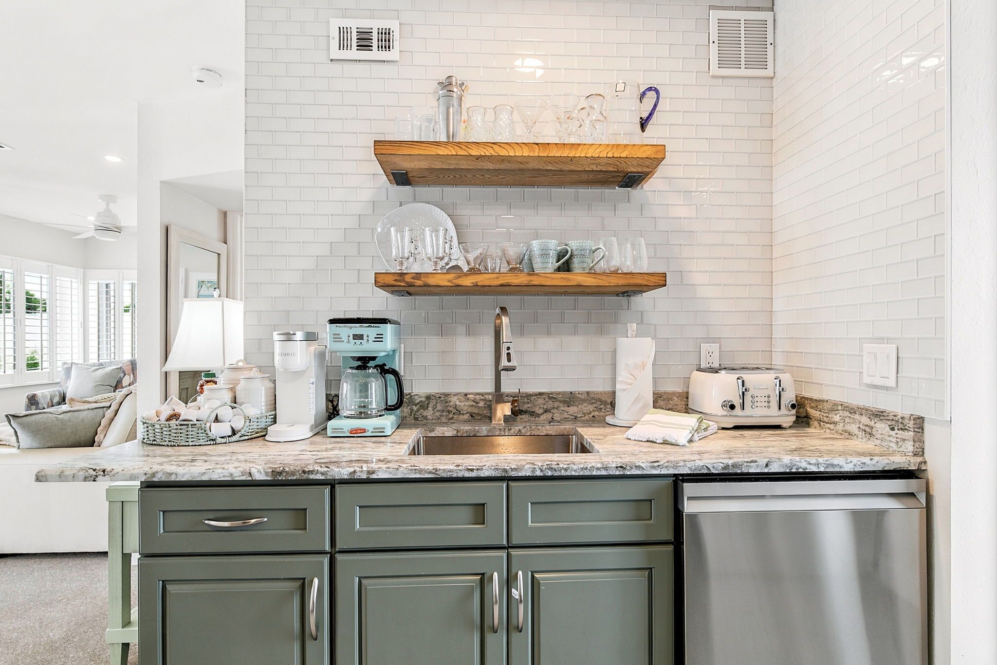 Cozinha com bancada de mármore, eletrodomésticos de aço inoxidável e painel de backsplash de tijolos brancos.