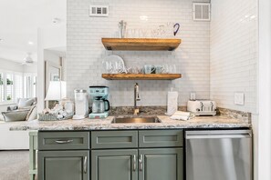 A kitchen with a marble countertop, stainless steel appliances, and a white brick backsplash.