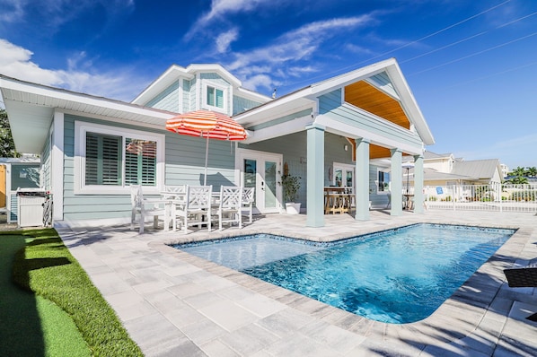 A modern house with a swimming pool, outdoor seating, and a covered patio area.