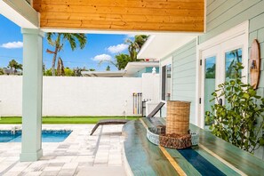 Un espacio al aire libre techado con piscina, techo de madera, una cesta de mimbre y una planta.