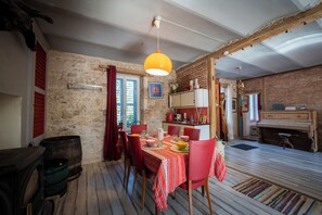 A rustic dining area with a wooden table, red chairs, and a hanging light fixture.