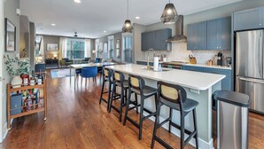 A modern kitchen with a central island, bar stools, and stainless steel appliances.
