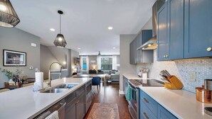 A modern kitchen with a central island, blue cabinets, and stainless steel appliances.