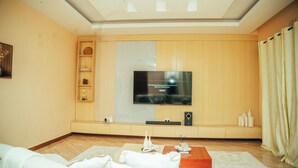 Una sala moderna con un televisor de pantalla plana en la pared, paneles de madera, un sofá, una mesa de centro y objetos decorativos.